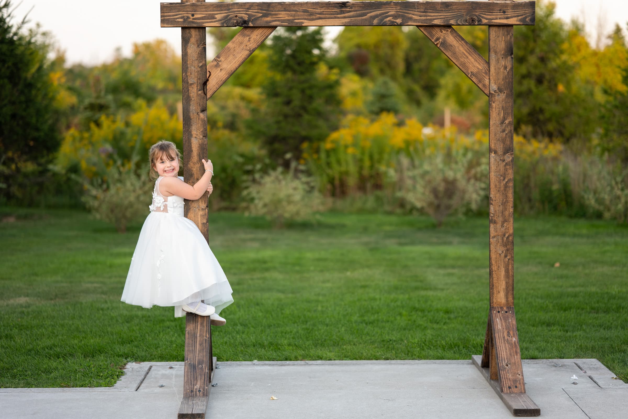 Cute girl climbs arbor at Pamona Blue Barn in Hilton, NY | Rochester Wedding Photography